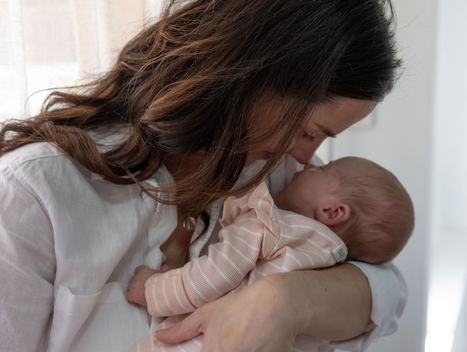 Mother gently touching babies nose with her own in a bonding moment between parent and child.