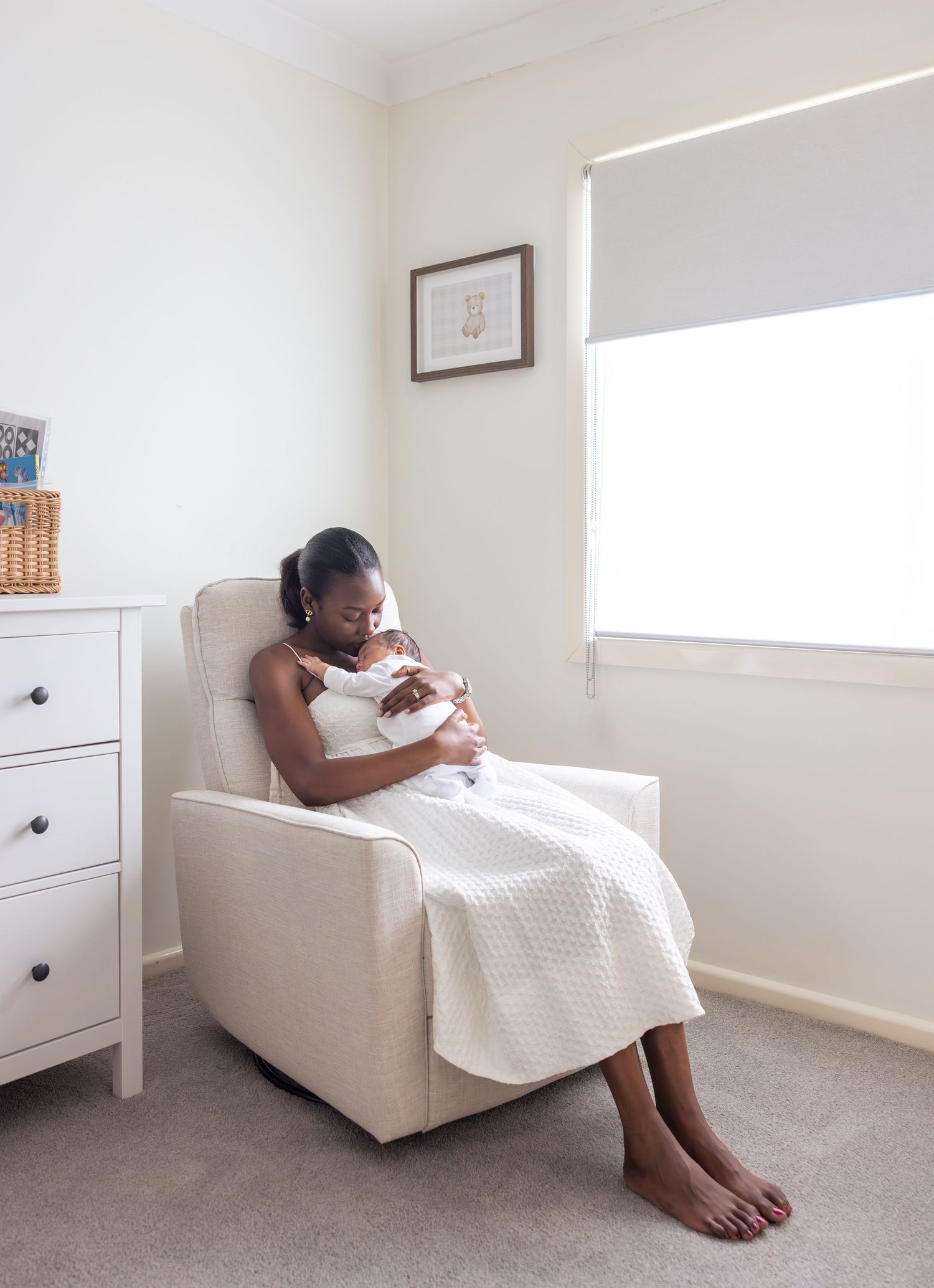 Mother sitting in a rocking chair in her home holding her newborn baby, rocking him to sleep.