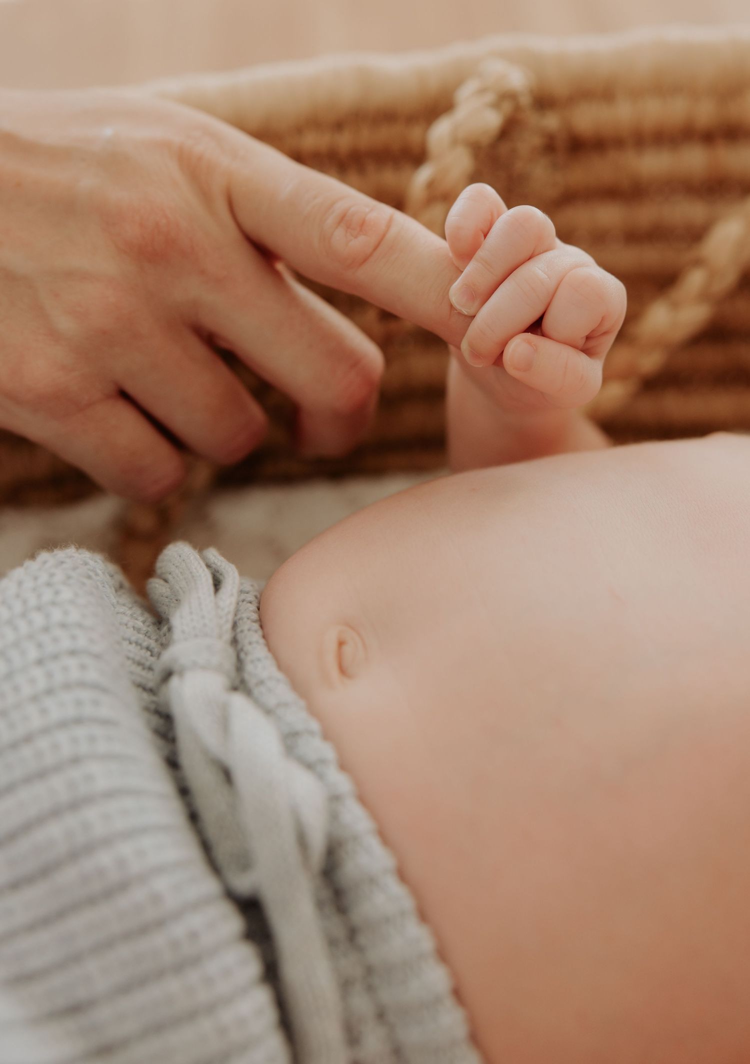 Close up ofewborn baby fingers softly wrapping around mothers finger.