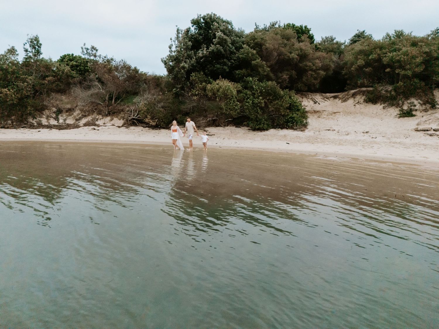 Family walking at the edge of Grannies pool in Blacksmiths. Captured by drone.