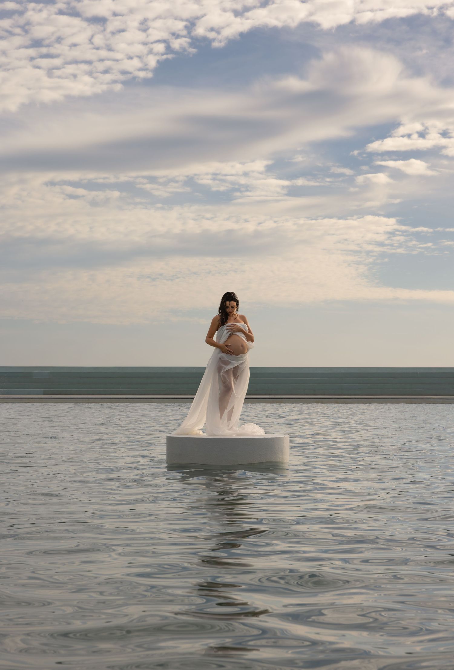 Newcastle Ocean Baths platform in the middle of the water with woman standing and posing on top.