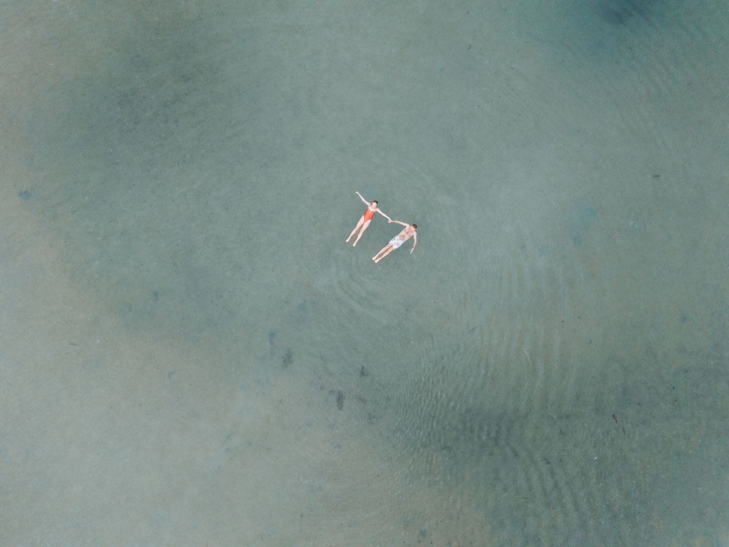 Woman and man float is calm waters taken from above.