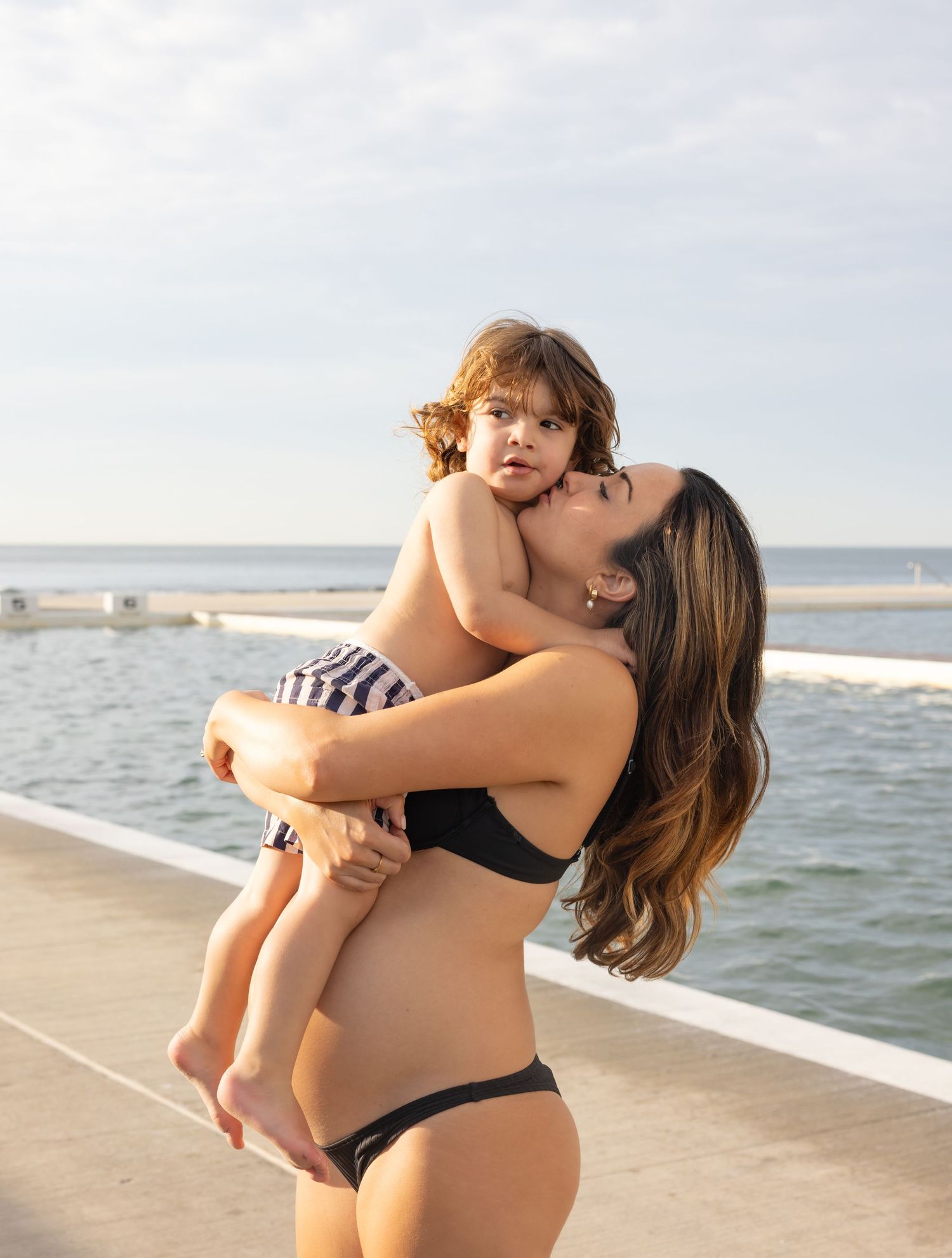 Mother holds child close during golden hour.