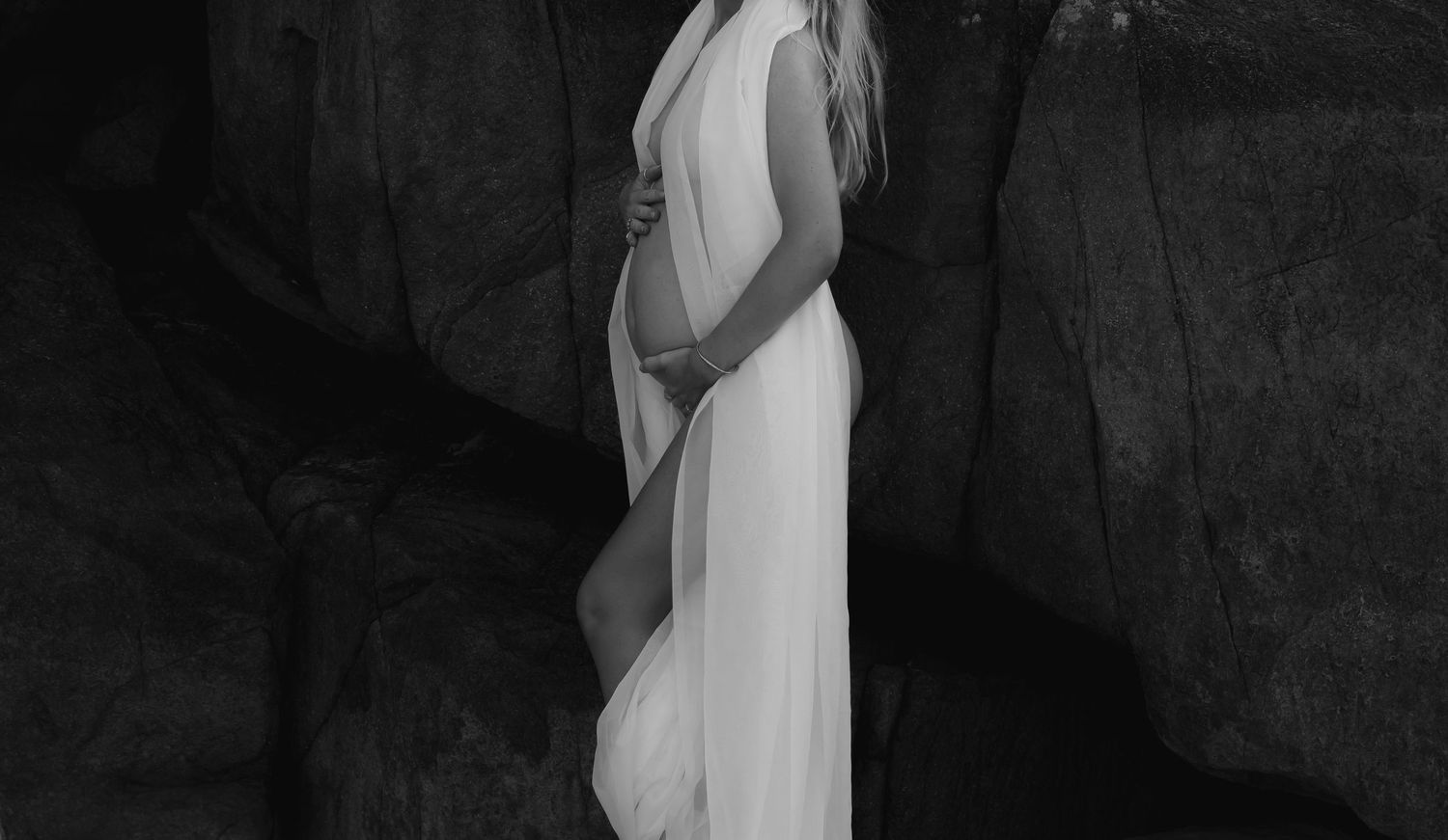 Pregannt mum holds belly wrapped in soft fabric.