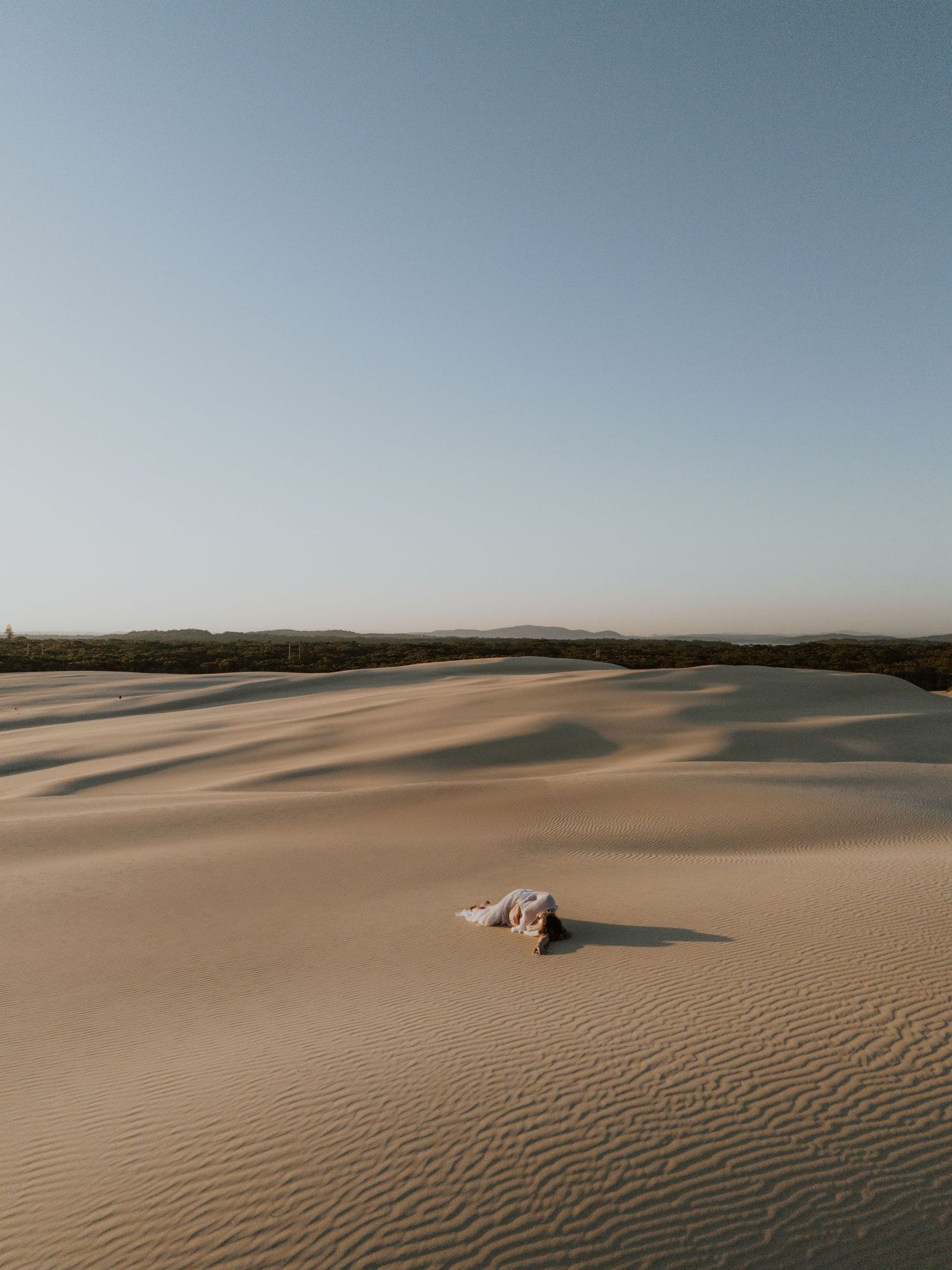 Drone image of a mother laying in the middle of the sand dunes at Stockton which stretch on forever.