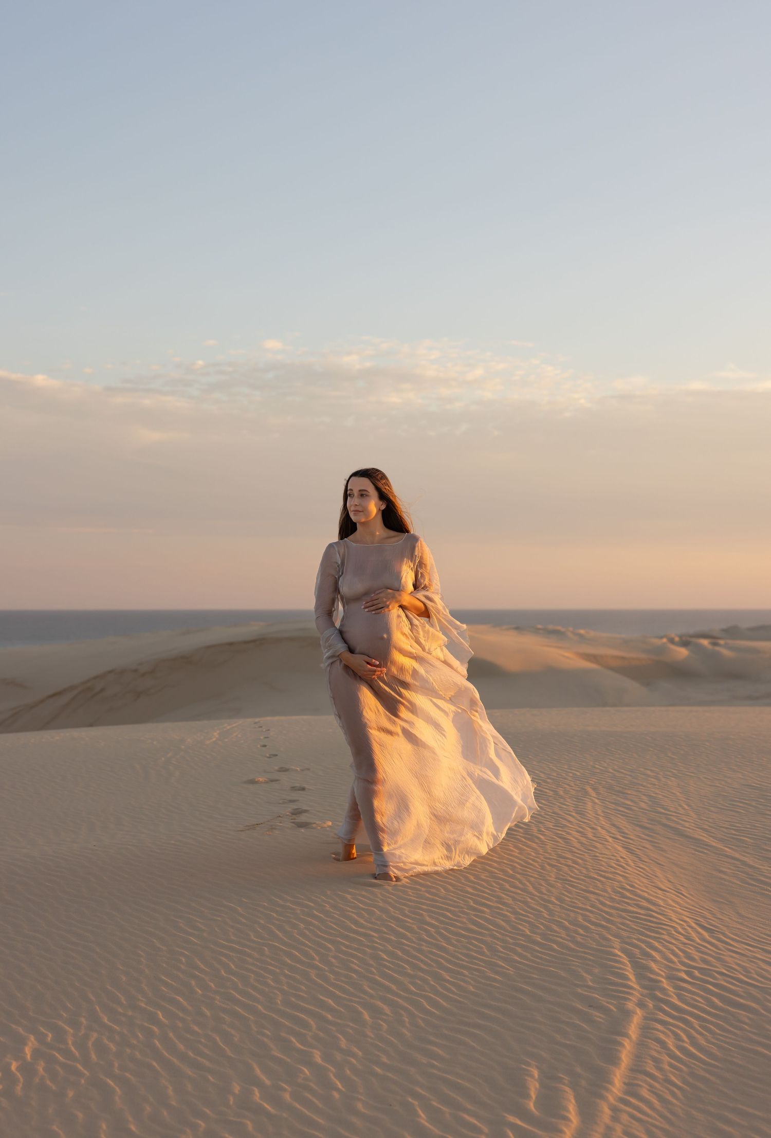 Maternity mother illuminated by the soft golden sunset at the Stockton sand dunes.