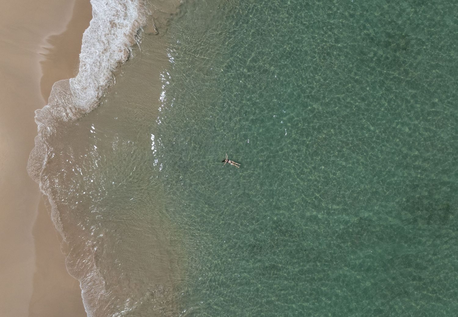 Drone image taken from high in the air of crystal clear waters and waves.