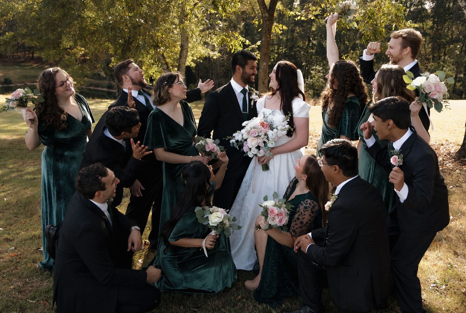 Wedding party poses together in front of ornate wooden doors on a sunny autumn day.