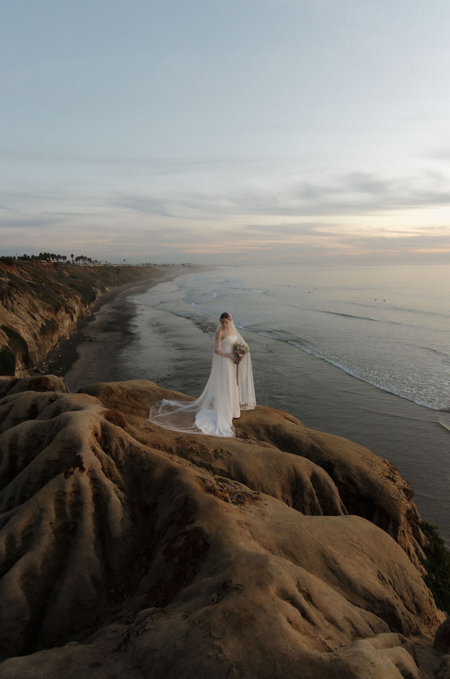 Dramatic coastal cliffs overlooking the ocean at sunset with misty horizon.
