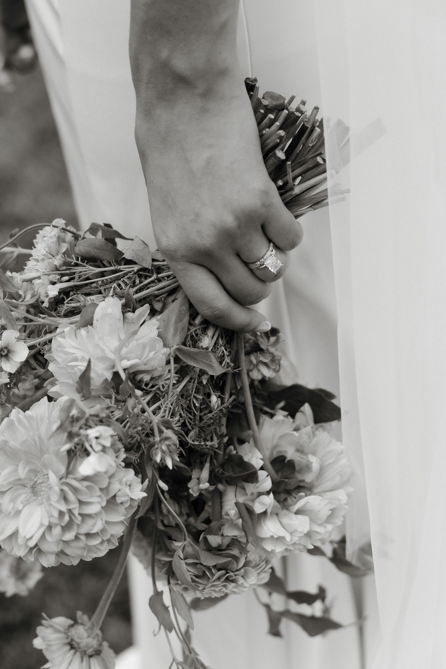 Close-up of hands holding a delicate white and pink floral wedding bouquet.
