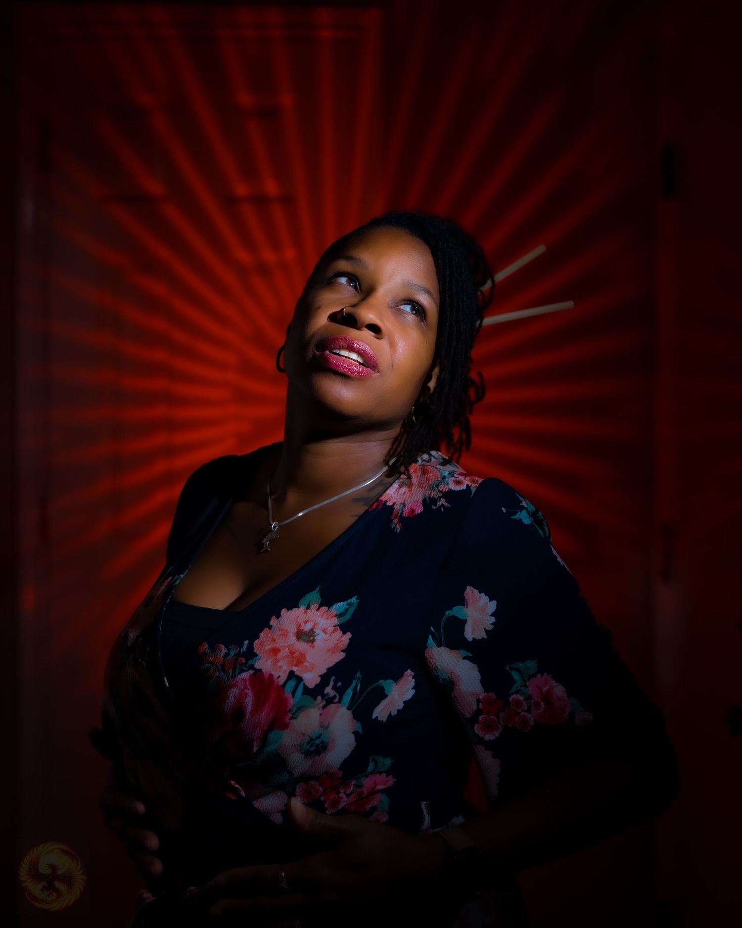 Dramatic portrait against red starburst background with floral dress details.
