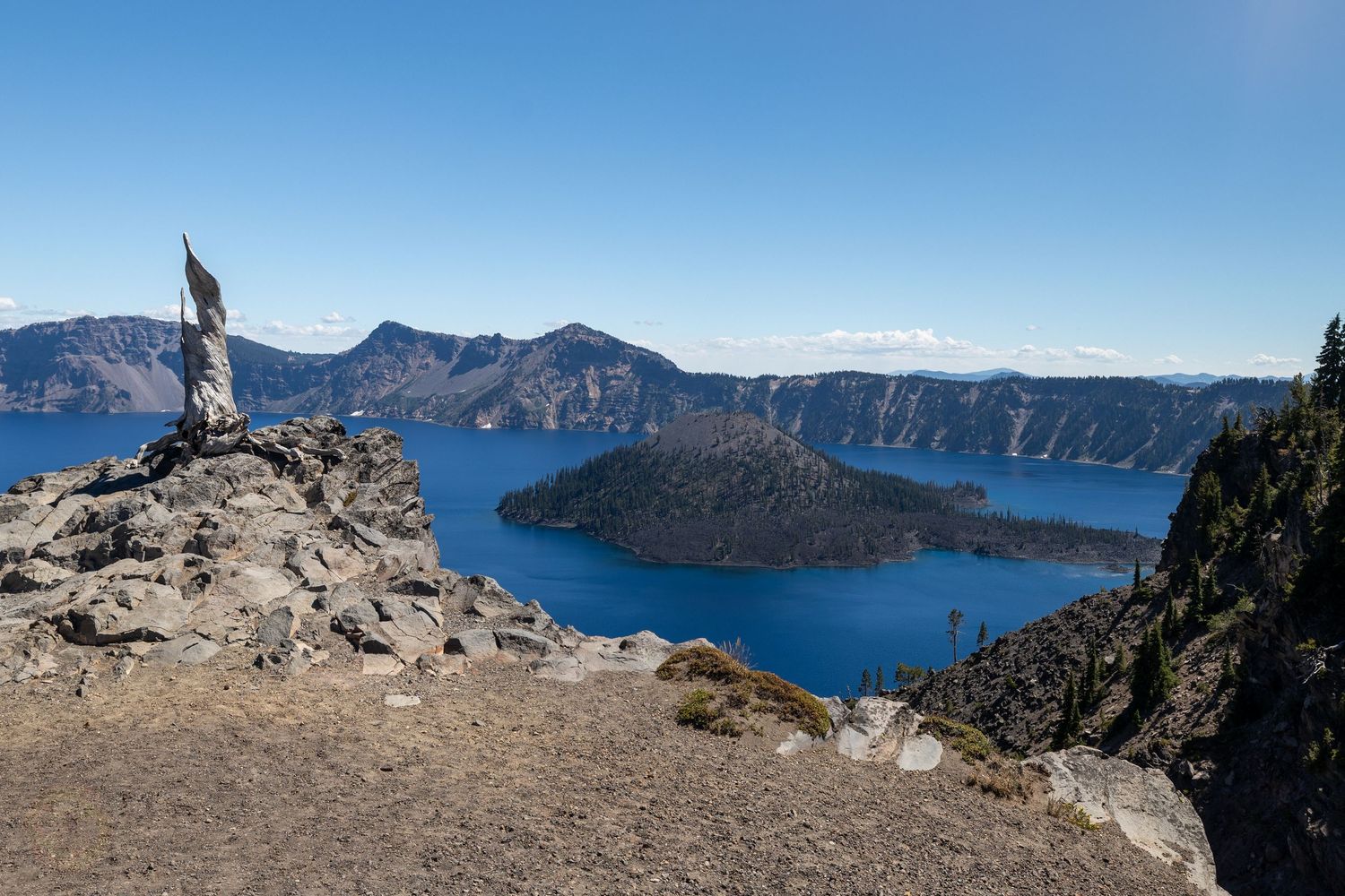Panoramic view of Crater Lake National Park with mountains and blue water.