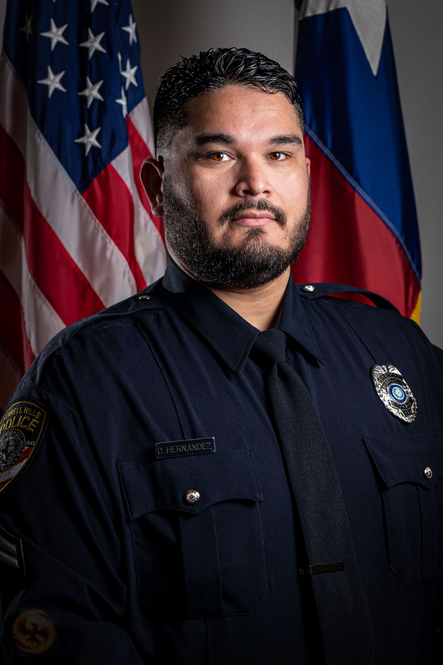 Official police officer portrait with American and state flags in the background.