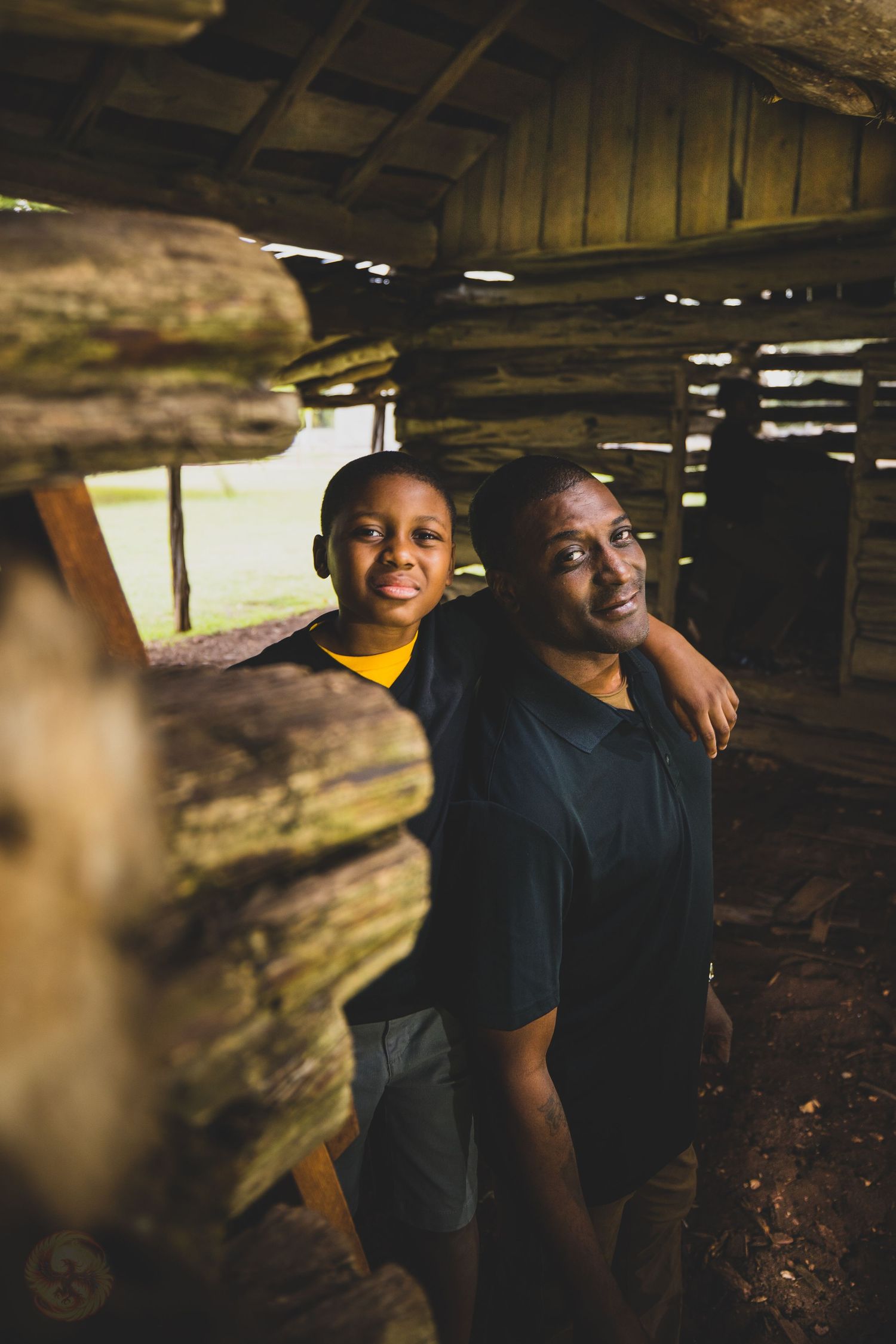 Couple posing together in rustic wooden setting with natural light filtering through.