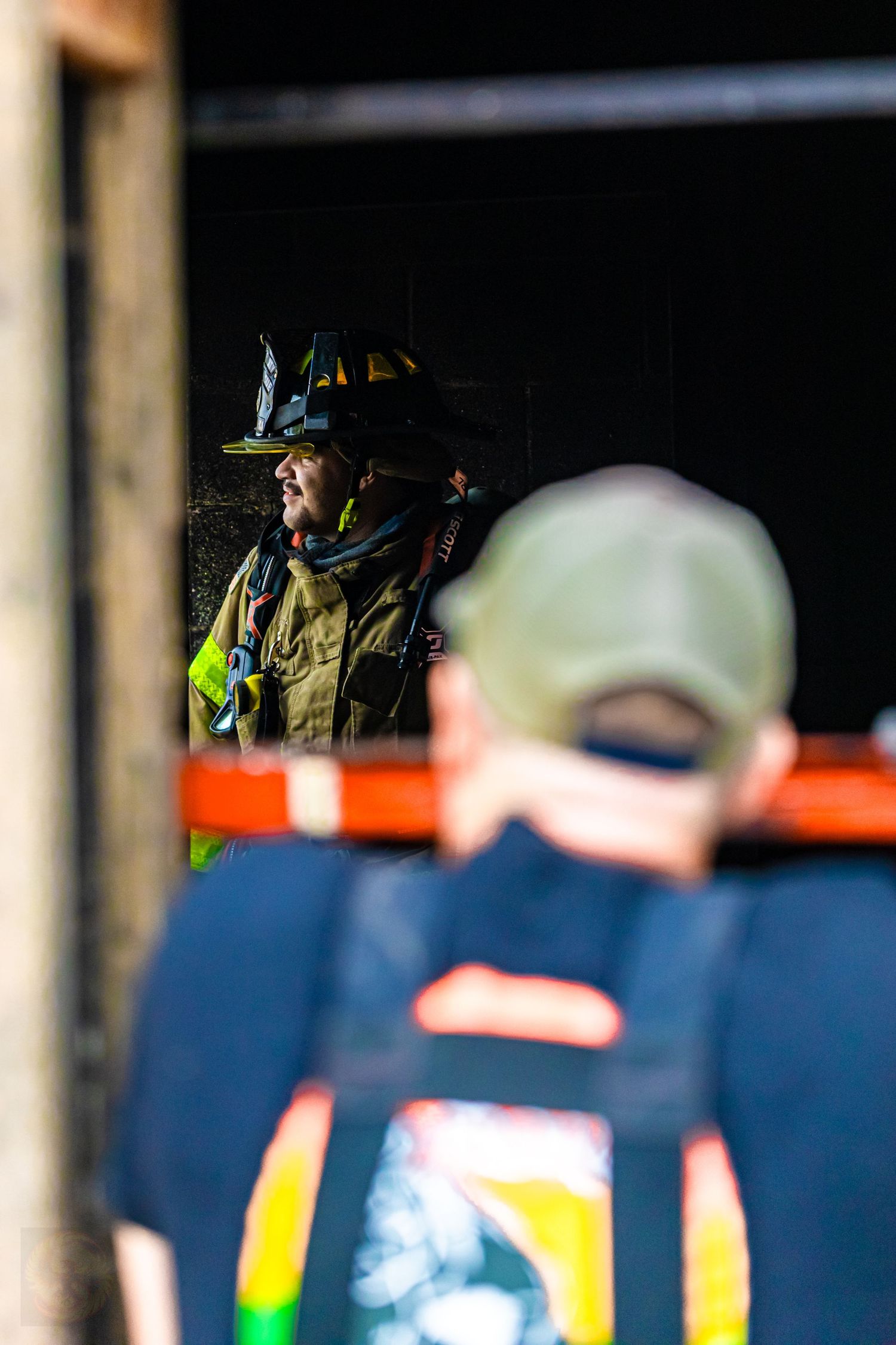 Firefighter in protective gear and helmet visible through a darkened doorway.