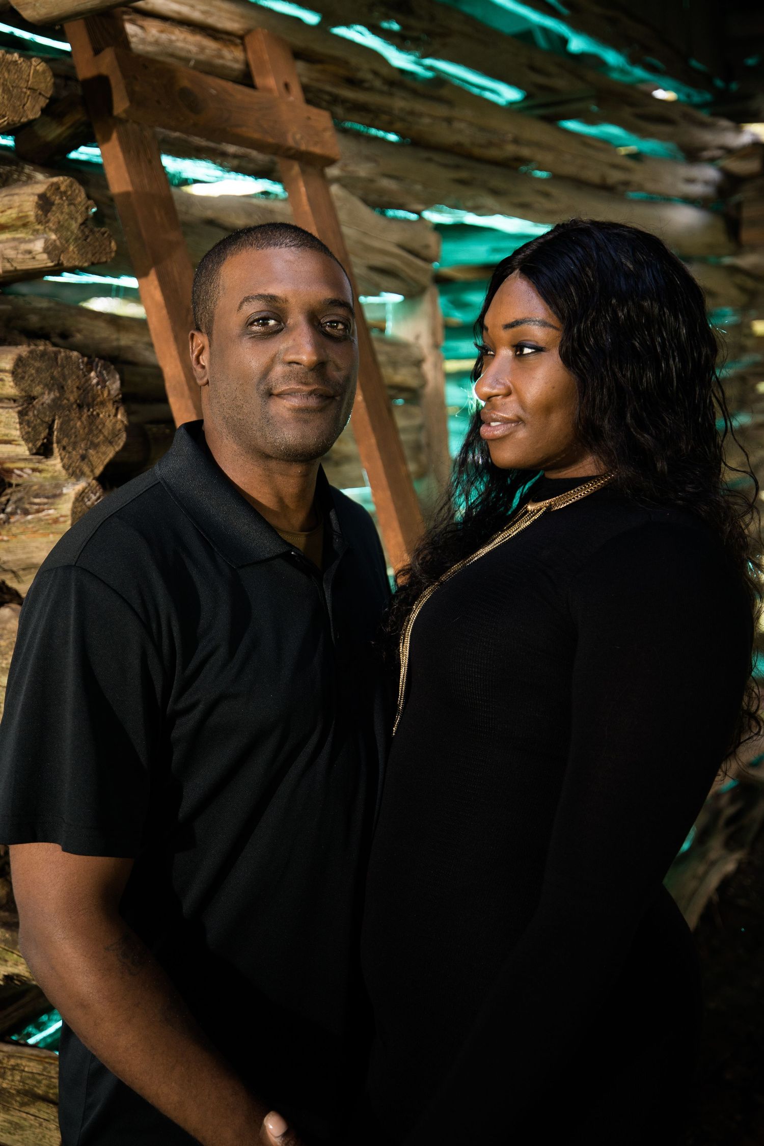 A couple shares intimate moments in a rustic setting with wooden beams and turquoise lighting overhead.