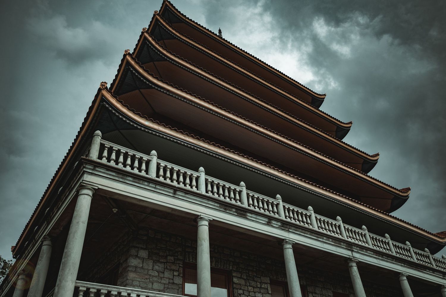 Dramatic low angle view of a building with columns under stormy skies.