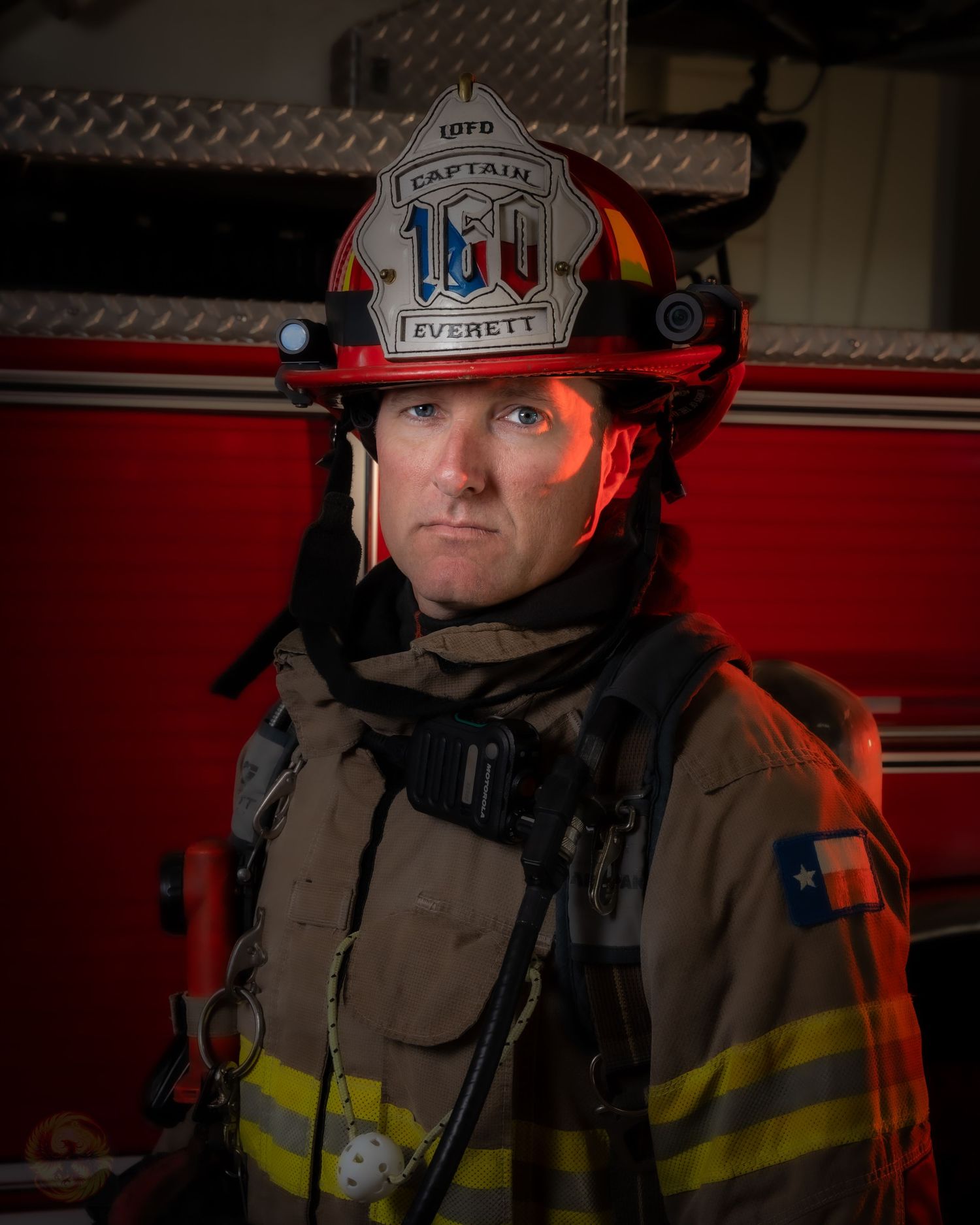 Firefighter in full protective gear and helmet with dramatic red lighting.