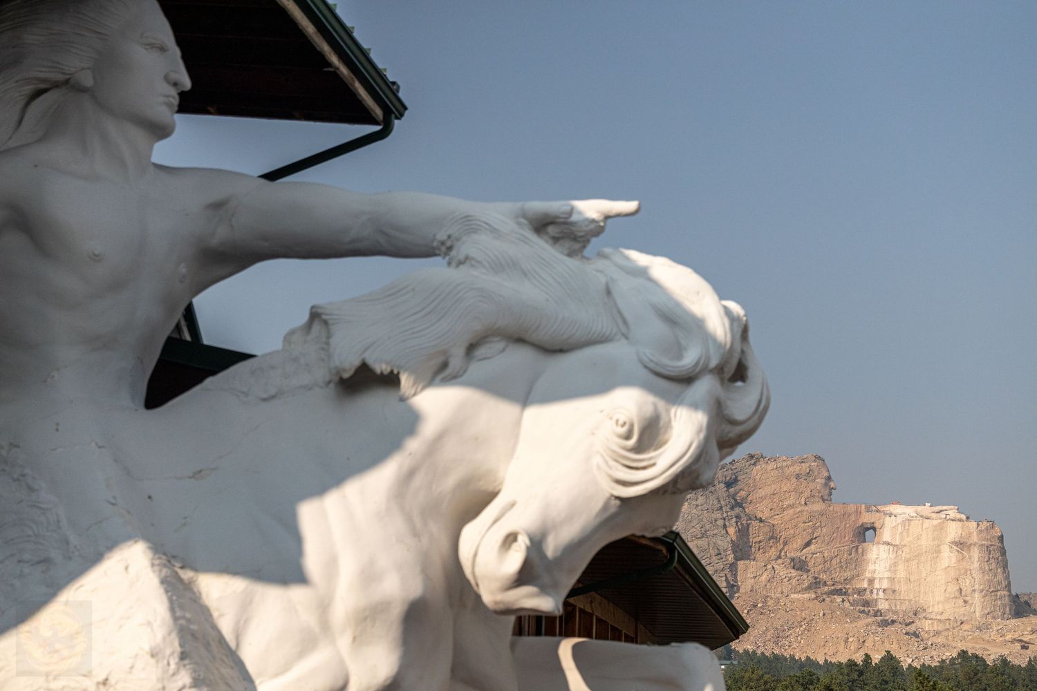 White horse statue silhouetted against a desert canyon landscape at sunset.