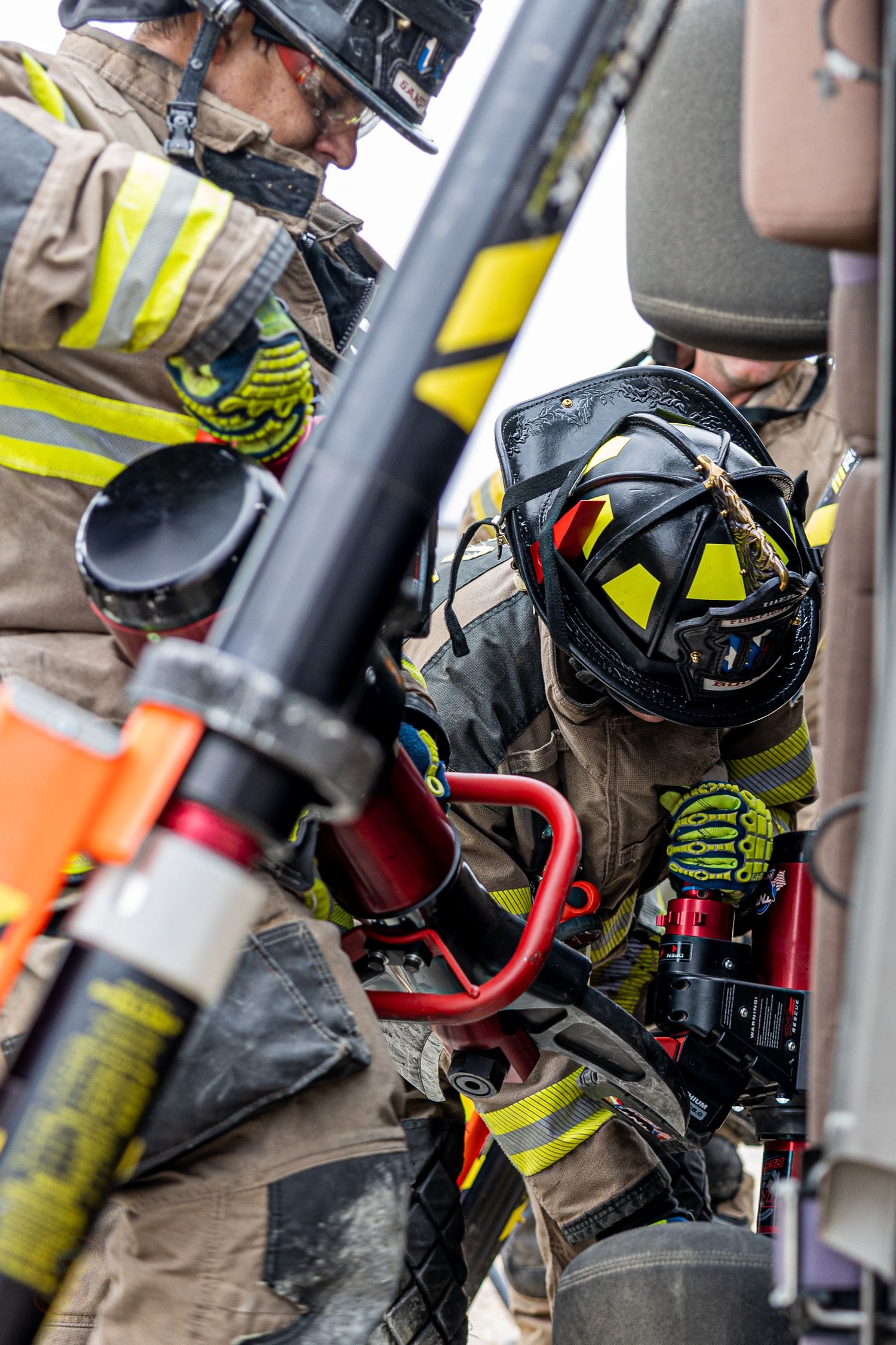Firefighter in protective gear and helmet working with equipment during an emergency response.