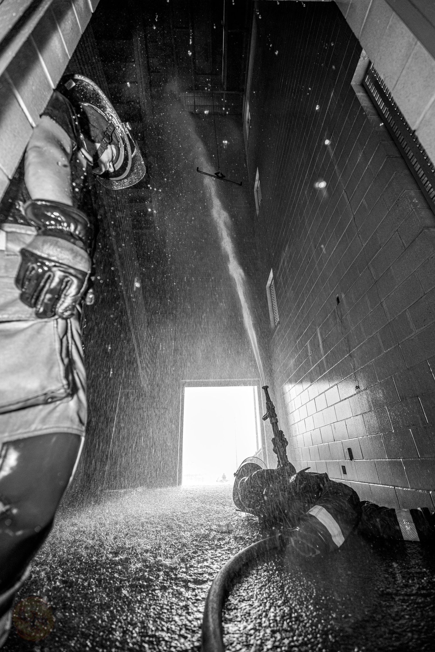 Black and white low-angle shot of water spraying in an indoor training facility.