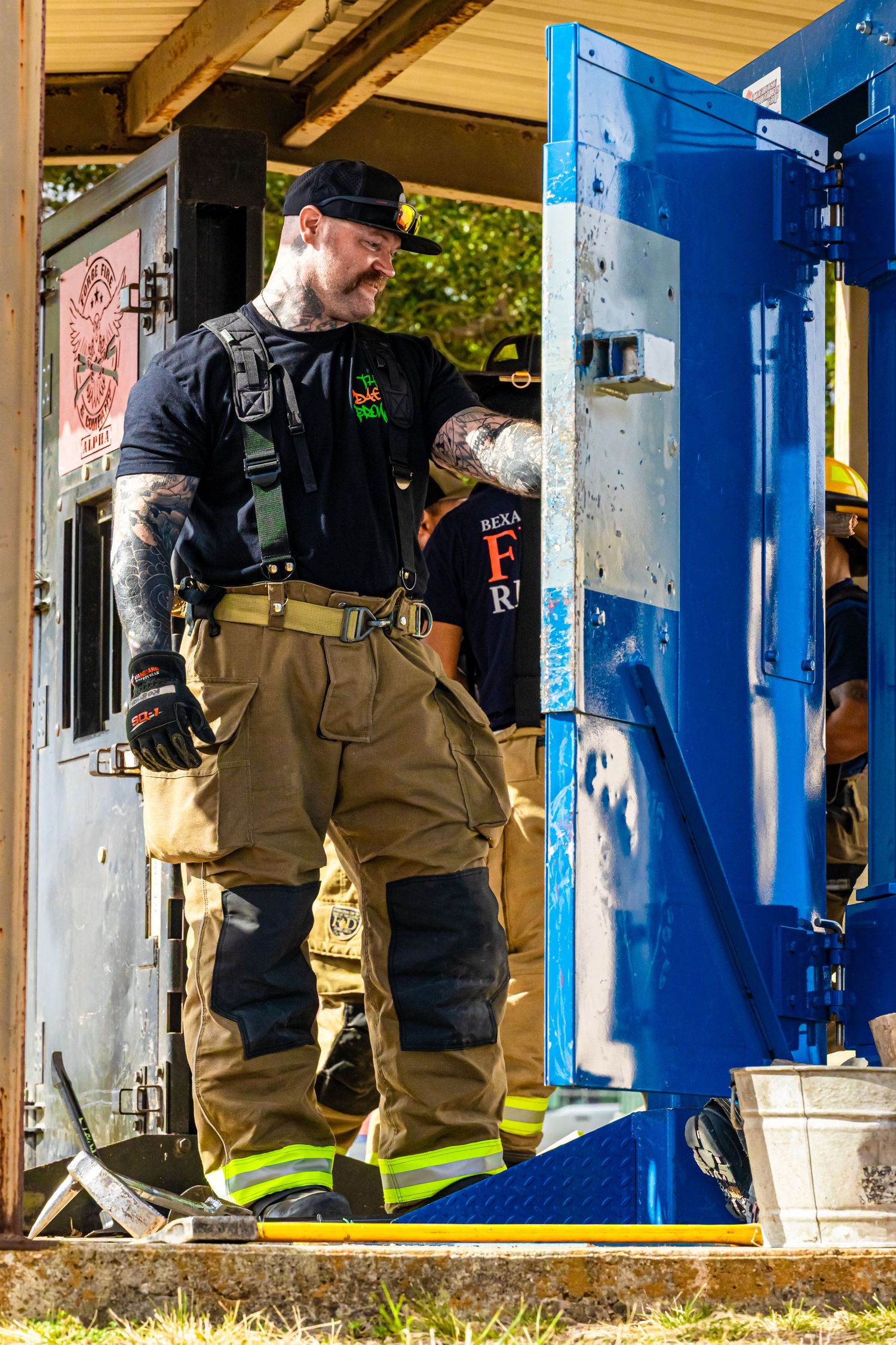 Firefighters in protective gear conduct training exercises at a facility with blue doors.