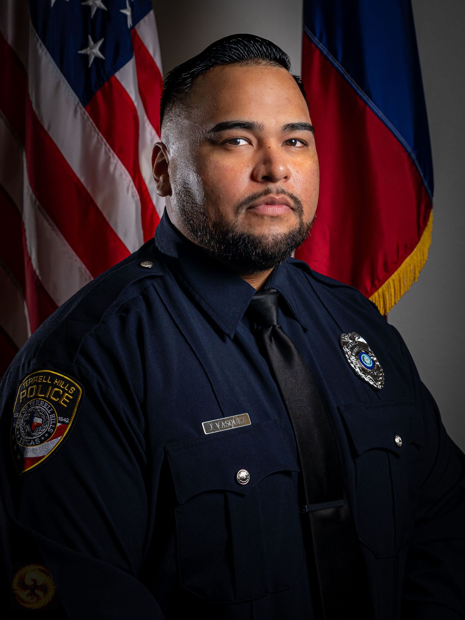 Official law enforcement portrait with American and state flags in background.