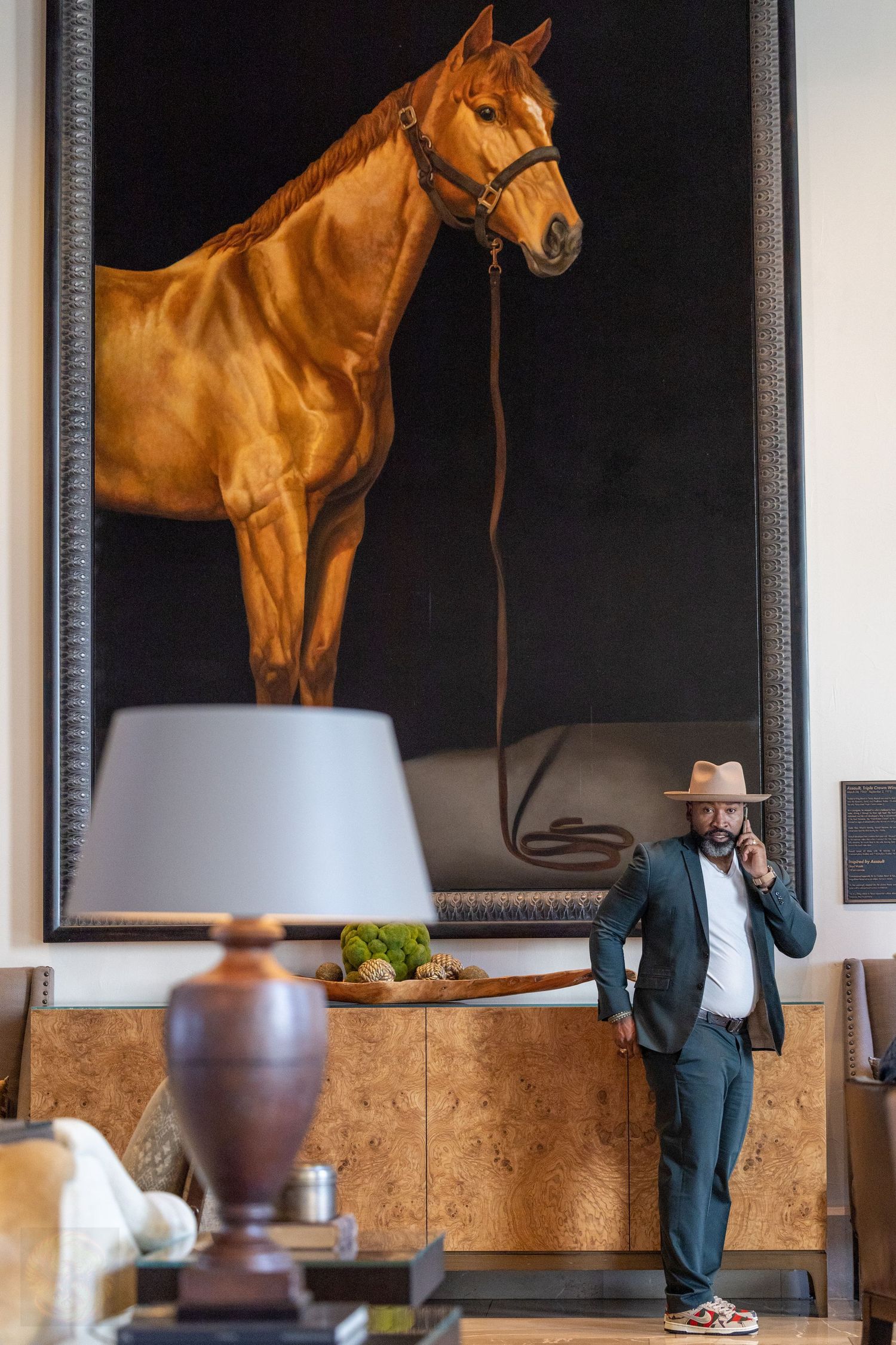Large horse painting displayed on wall with figure standing beneath.