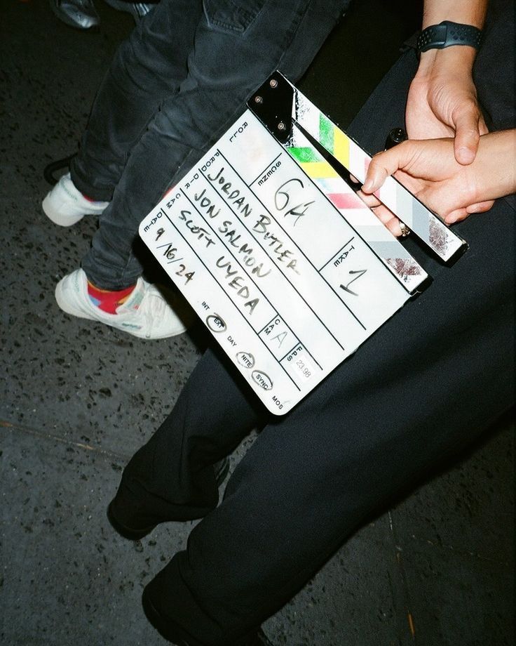Film crew member holds movie clapperboard on set during professional video production shoot.