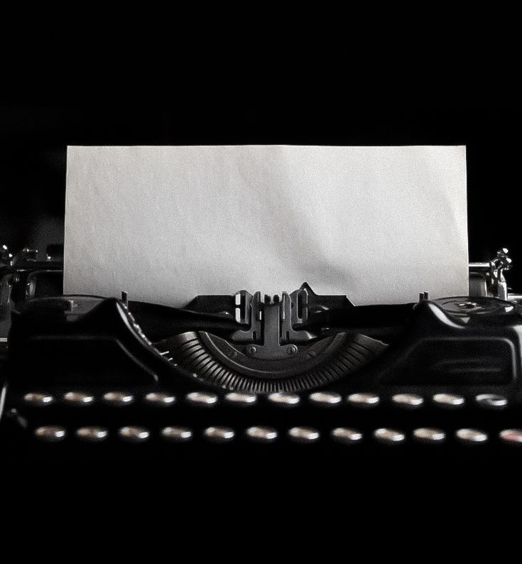Vintage black typewriter with blank white paper inserted, captured in dramatic black and white photography.