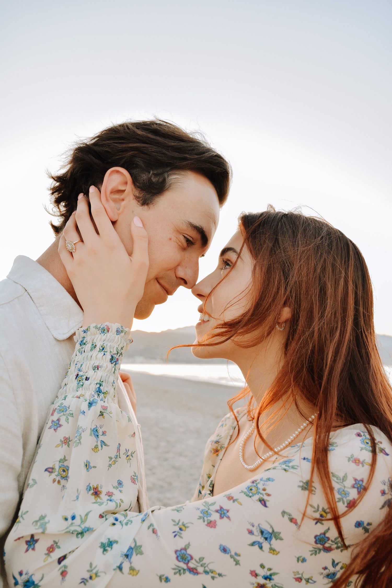 Romantic couple sharing an intimate moment on a beach, nearly kissing with eyes closed.