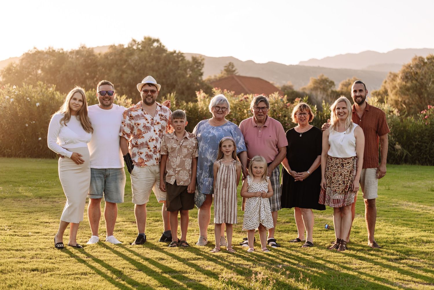 Large extended family group portrait outdoors at sunset in green field.