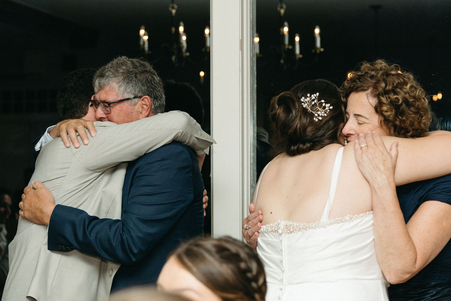 Emotional wedding reception moment with bride and guests sharing heartfelt hugs.