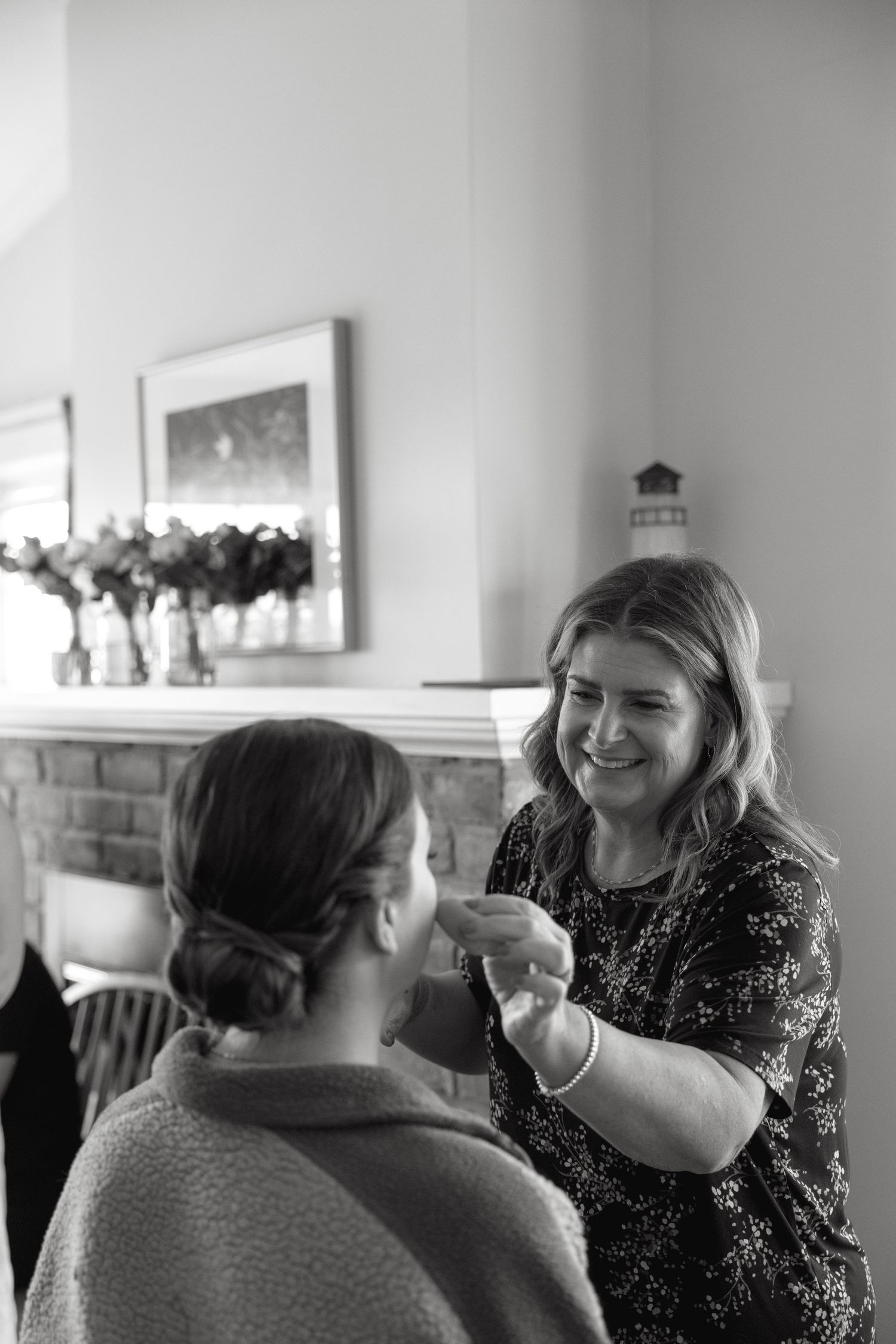 Makeup artist applying makeup to a bride during wedding preparations in a cozy room.