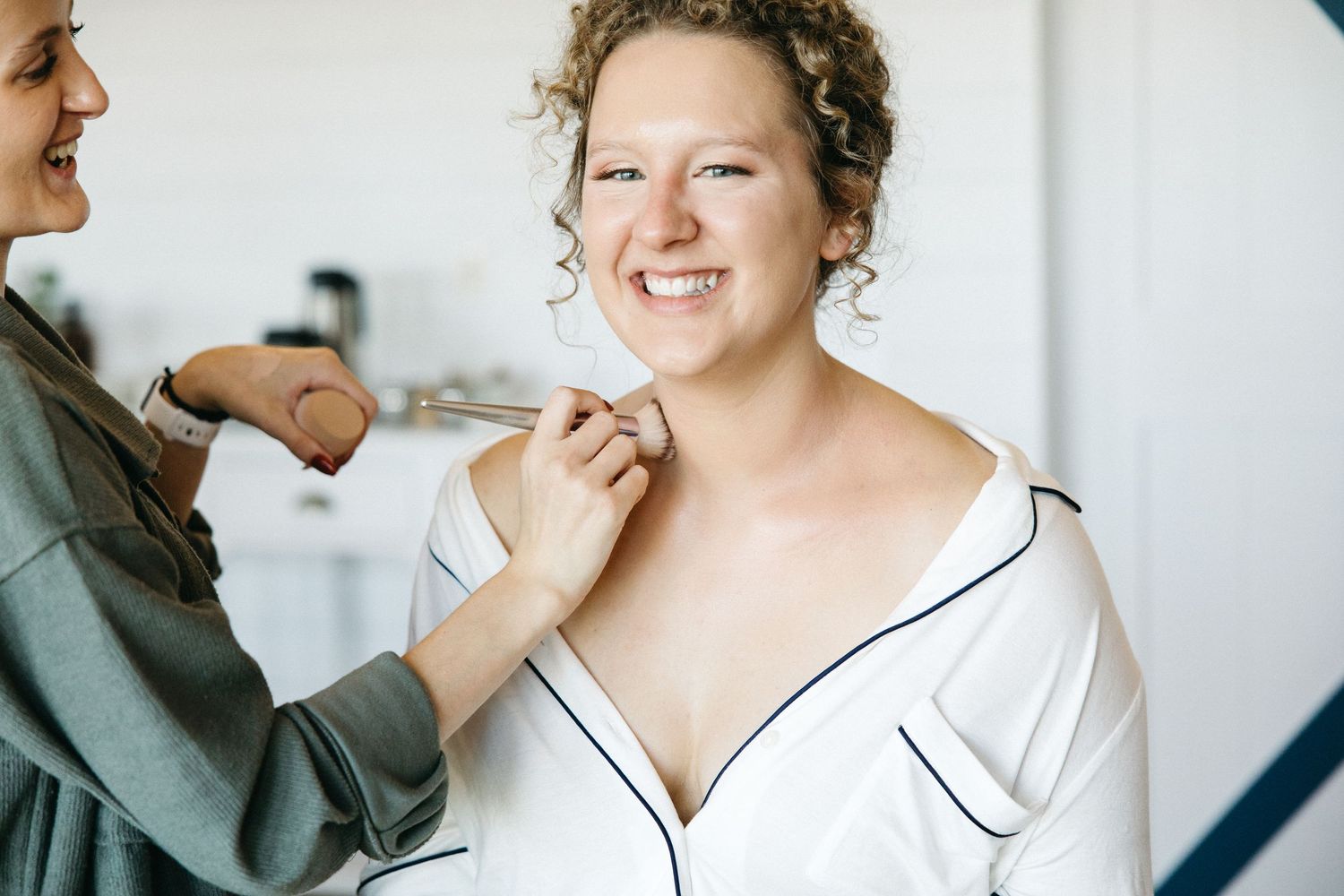 Getting ready scene with makeup application in a bright room with white decor.