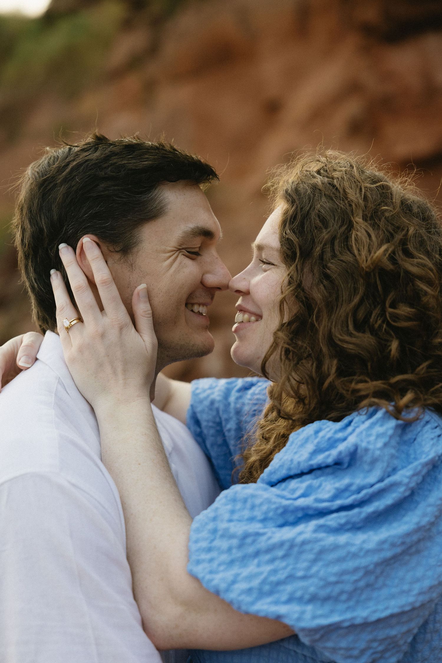 A tender romantic moment shared between a couple against a natural backdrop.