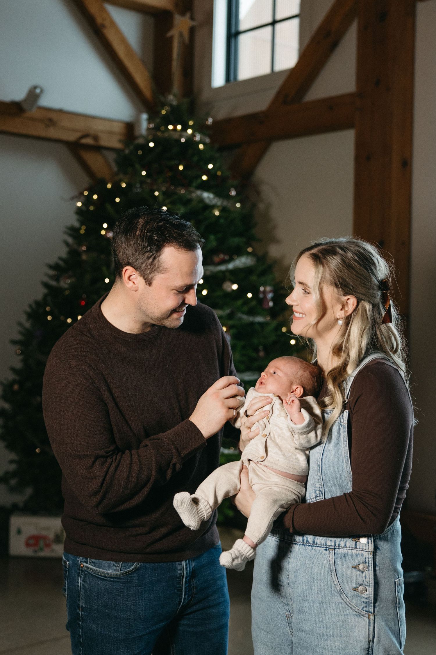 Loving family poses together in a rustic room with holiday decorations and wooden beams.