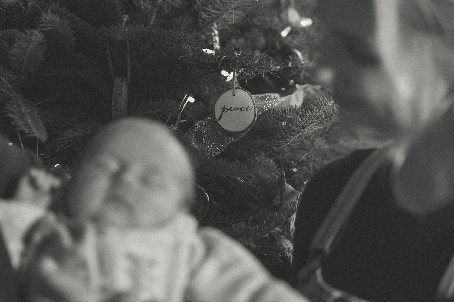 Black and white artistic photo of family moments near a Christmas tree.