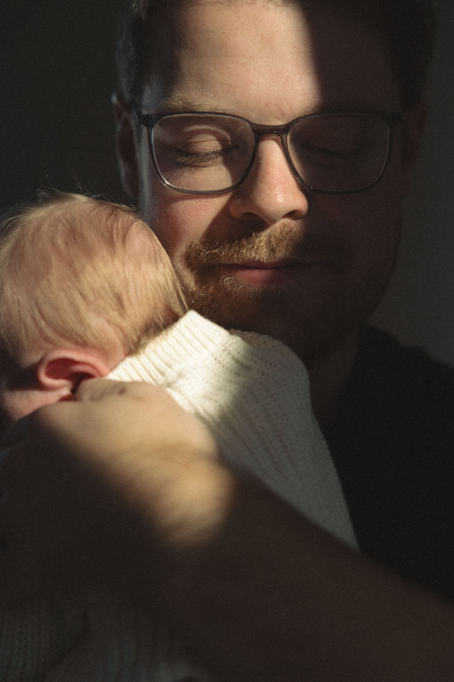Close up series of tender embraces between parent and baby in dim lighting.