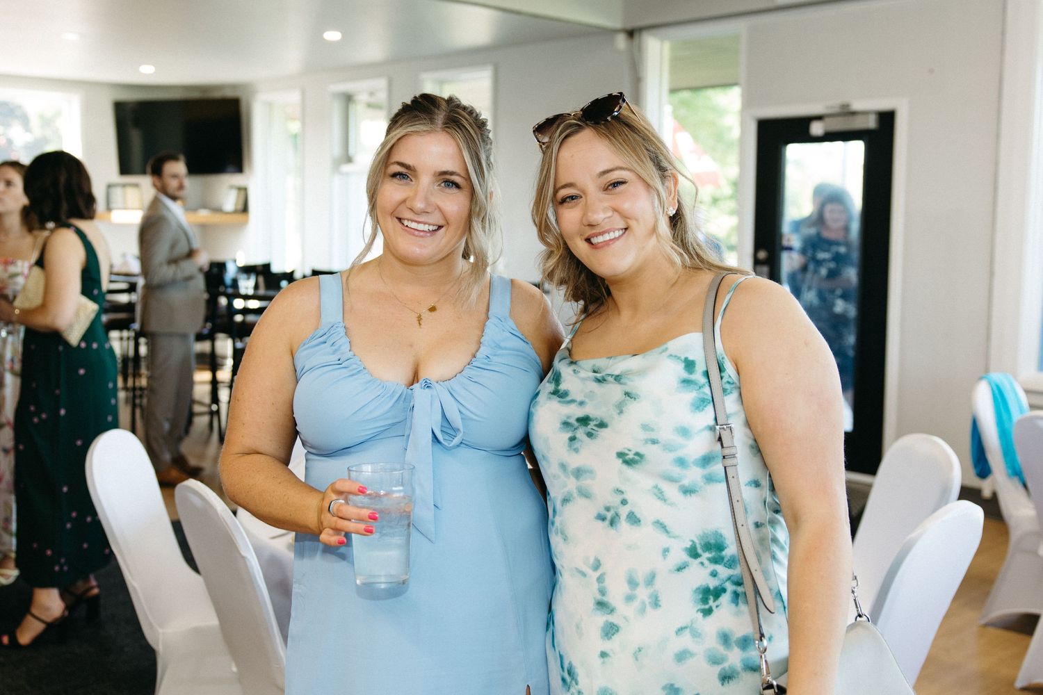 Wedding guests in light blue and floral dresses enjoying the celebration.