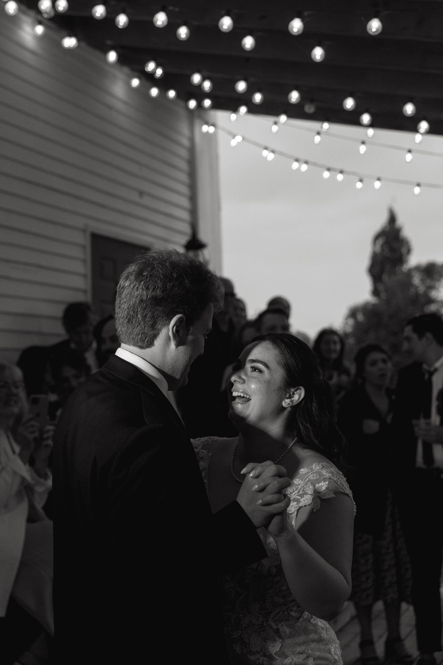 A couple shares their first dance under twinkling lights at their wedding reception.