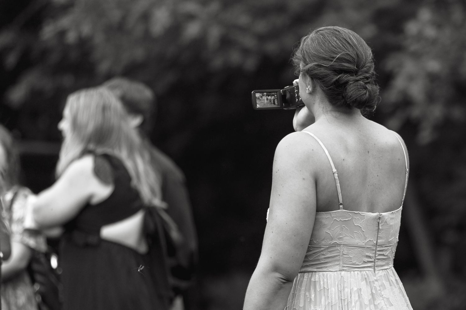 Black and white photo of guests mingling at an outdoor wedding reception.