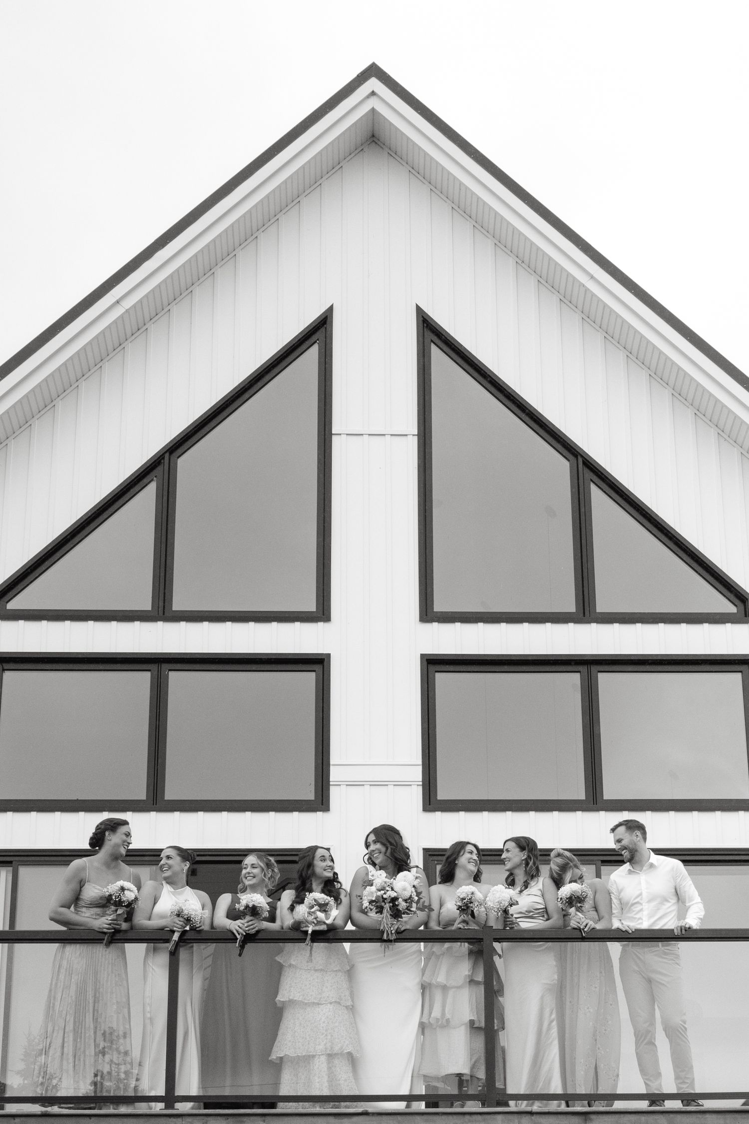 Wedding party lines up against geometric white building facades for a creative group photo.