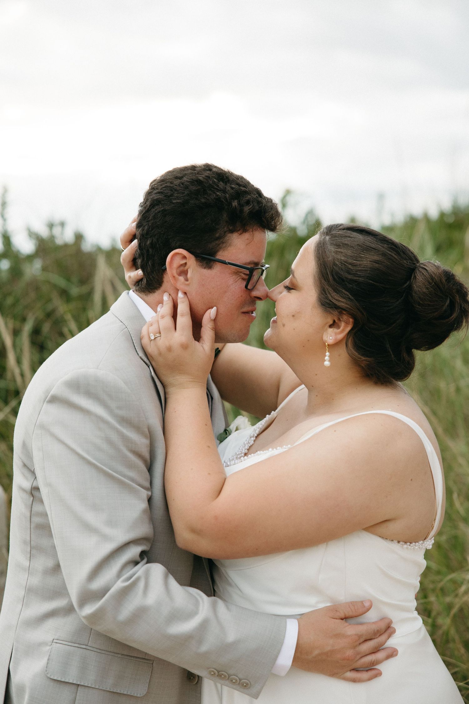 Bride and groom share tender moment embracing in lush outdoor setting.