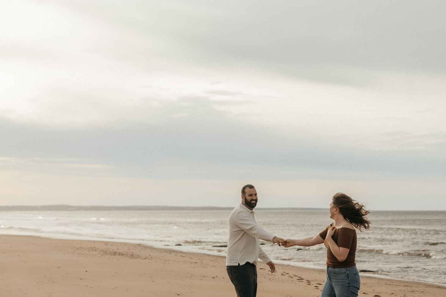 Couple walking hand in hand along the shoreline at dusk.