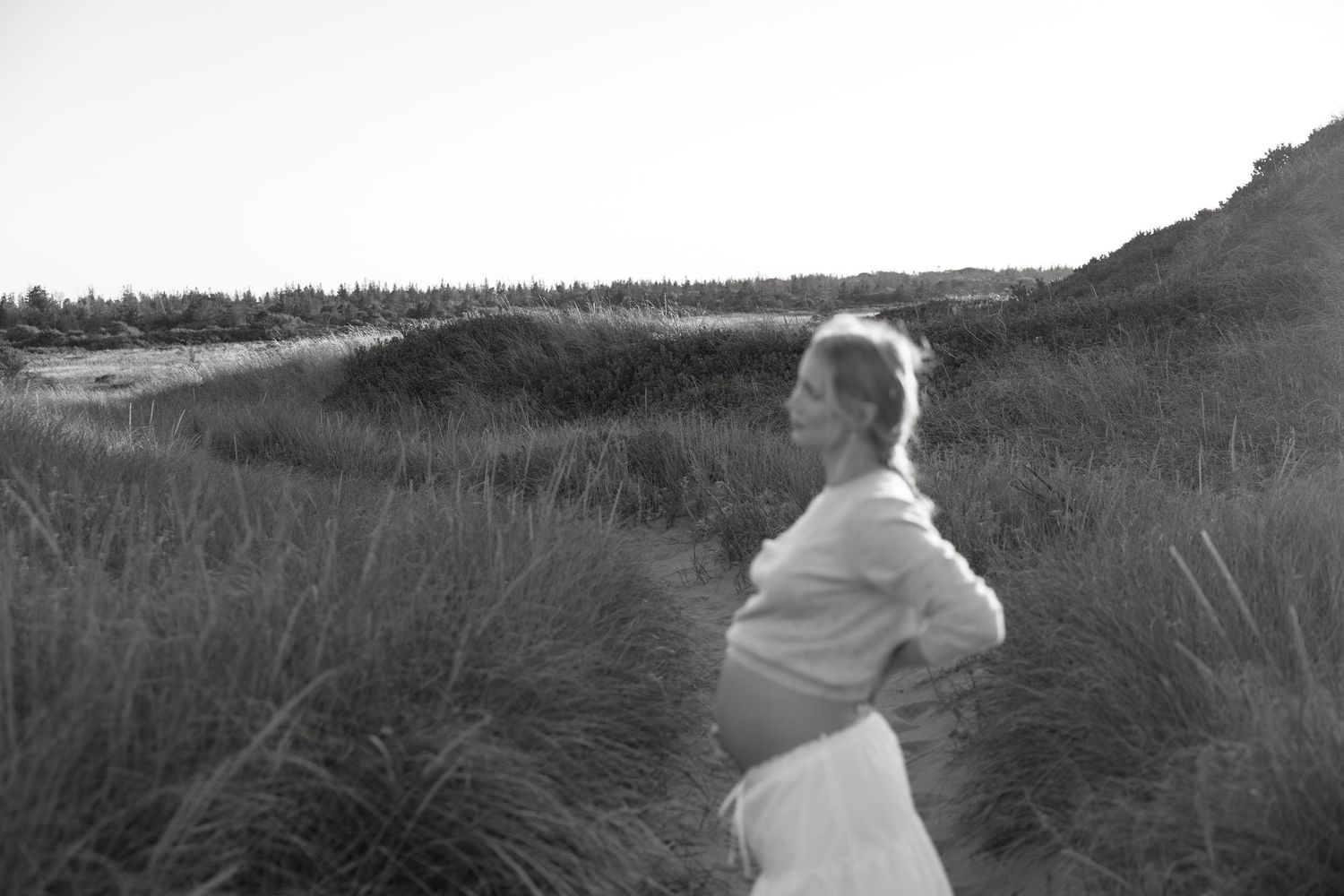Black and white artistic maternity portraits captured among beach grass and dunes.