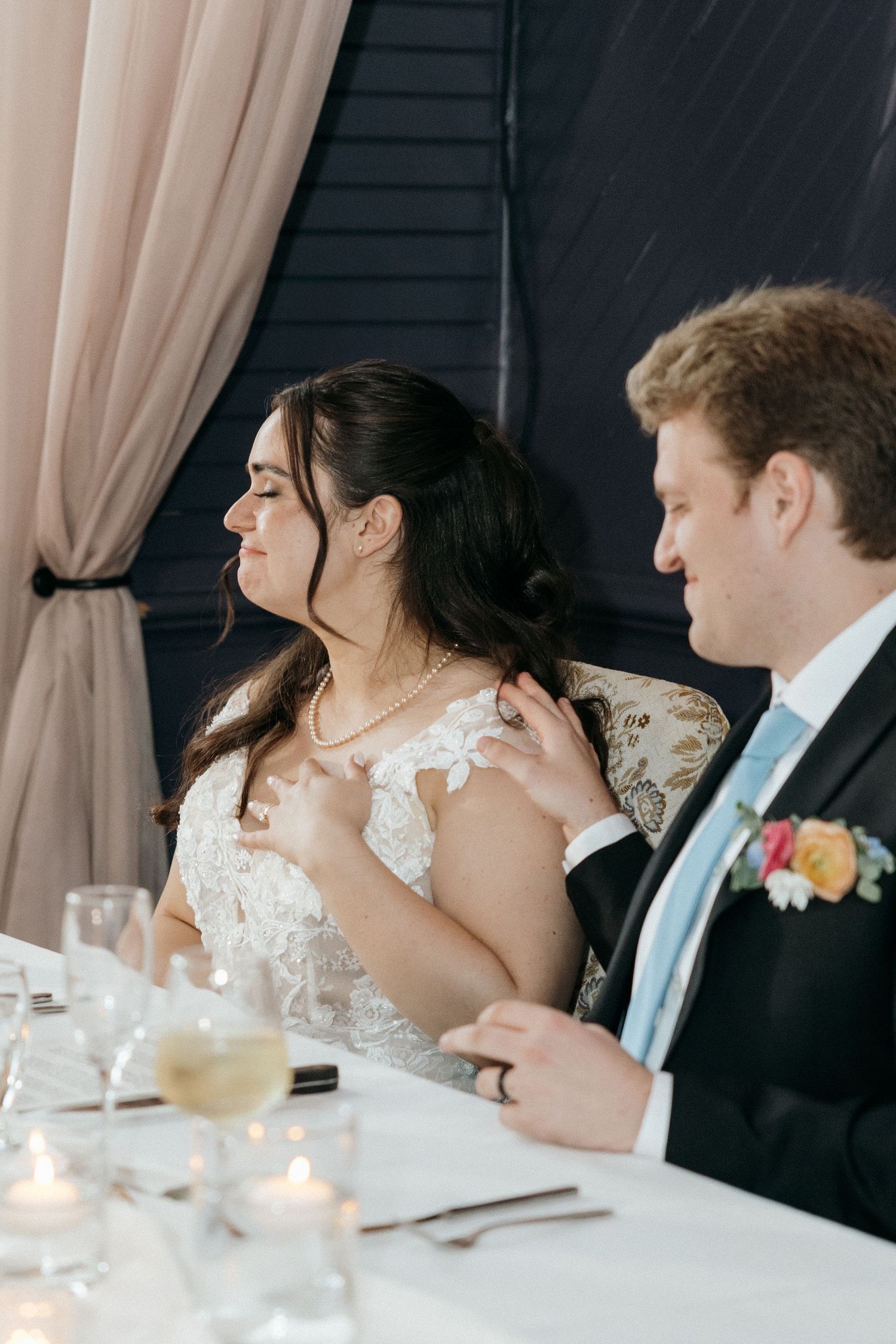 Wedding reception table setting with bride and groom enjoying dinner alongside guests at an elegant venue.