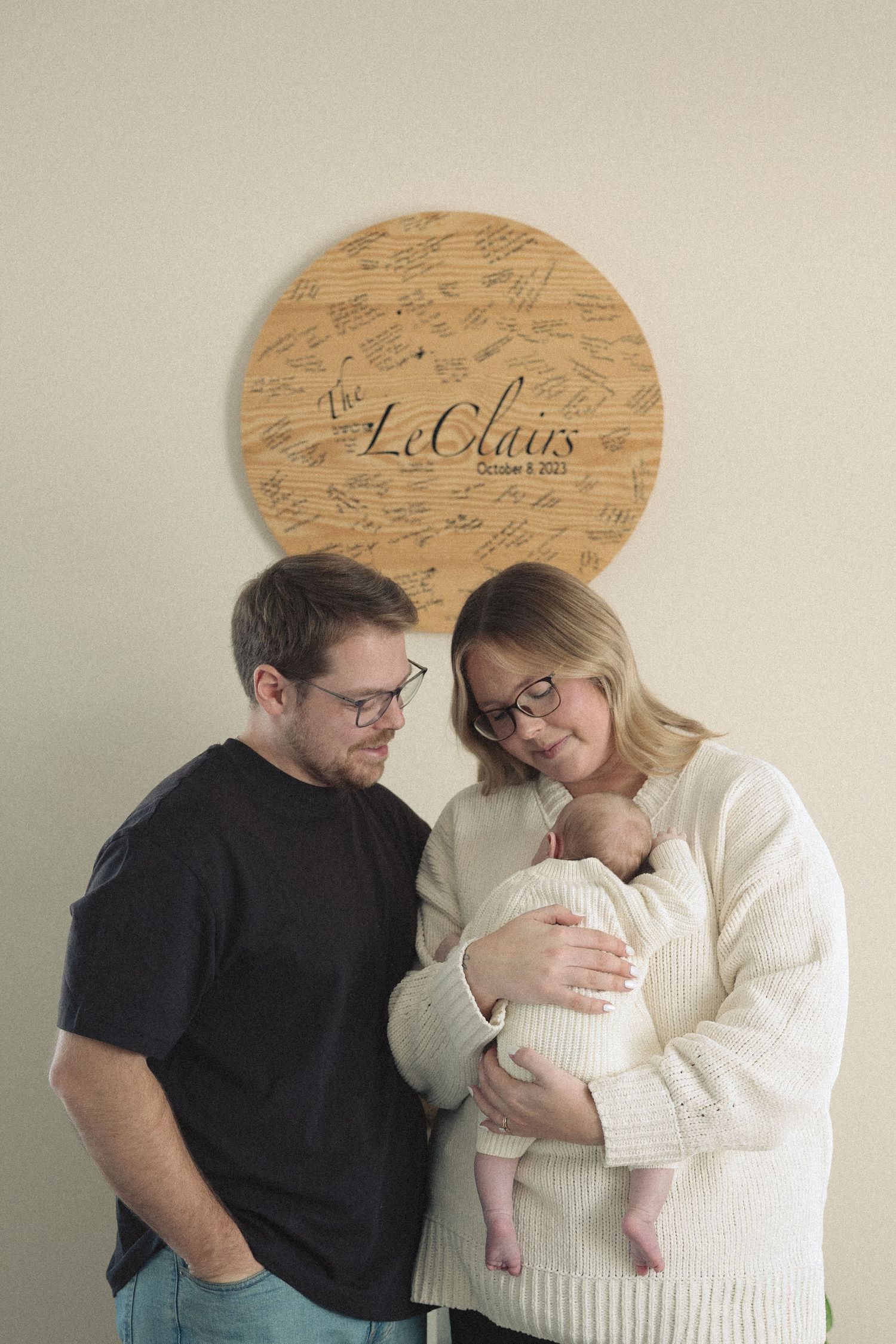A couple in black and white clothing share an intimate moment while holding their newborn baby.