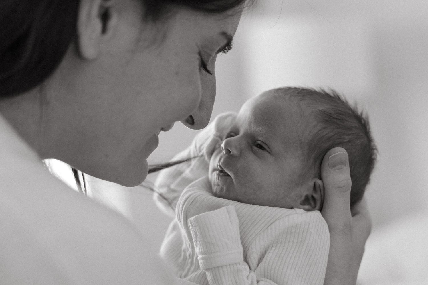 Black and white portrait of tender moment between parent and newborn.