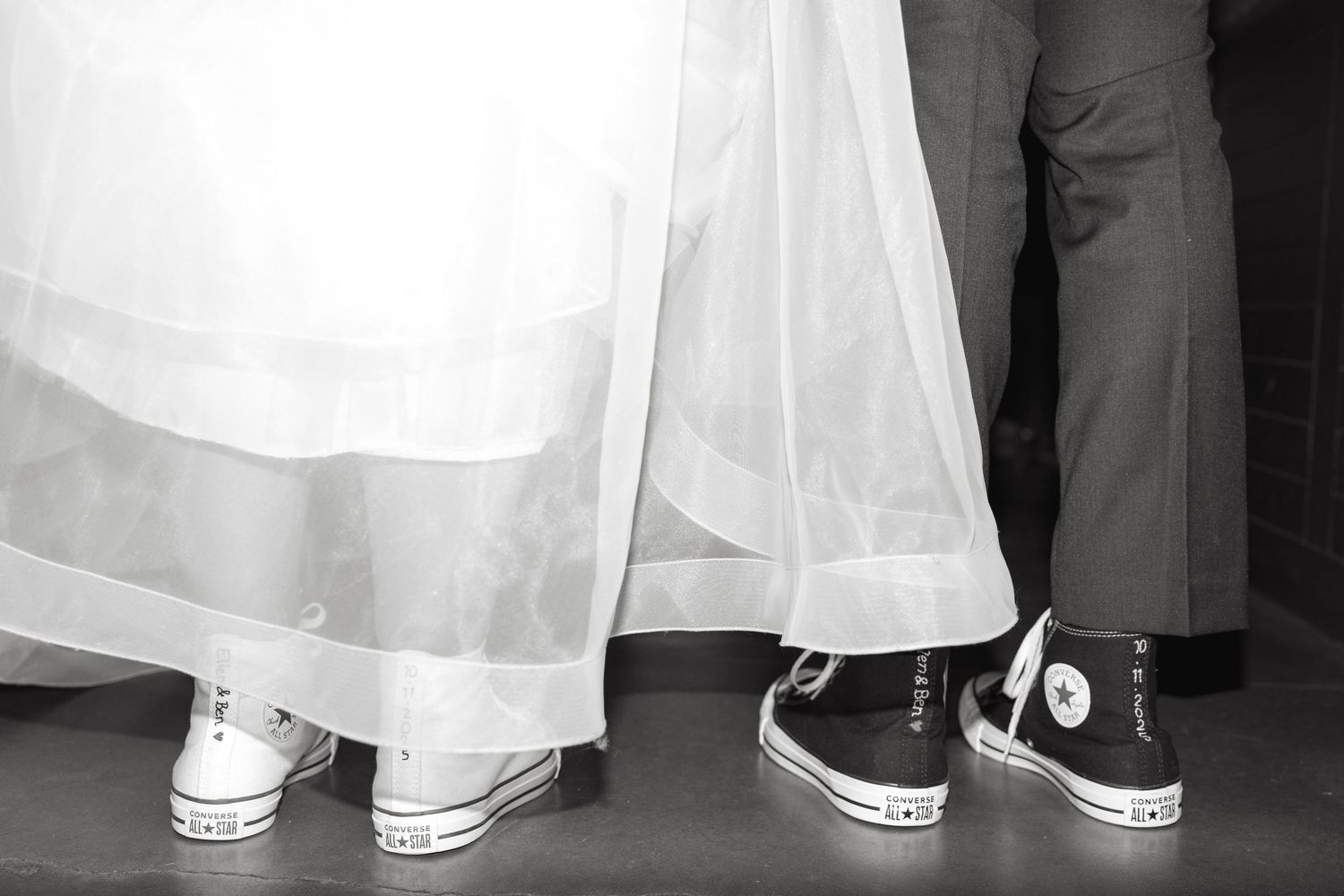 Row of formal white dresses and shoes visible from the knees down.
